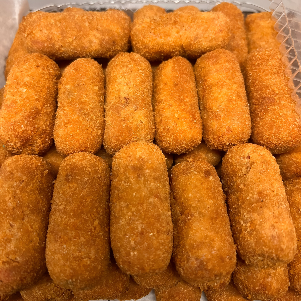 Close-up of a pile of golden-brown Cuban croquettes with a crispy breaded exterior.