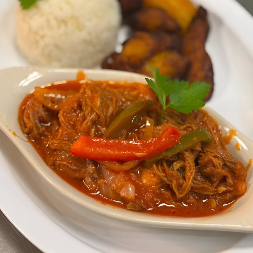 Cuban Ropa Vieja with shredded beef, red and green peppers, served with rice and plantains.