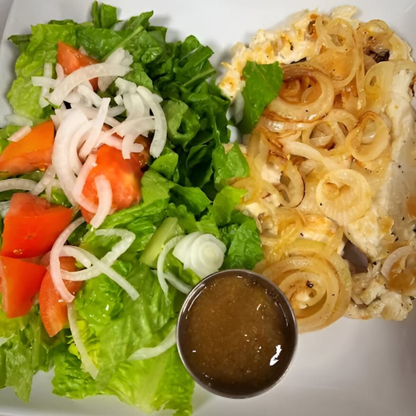 Cuban-style grilled chicken with caramelized onions, a side salad, and a cup of dressing.